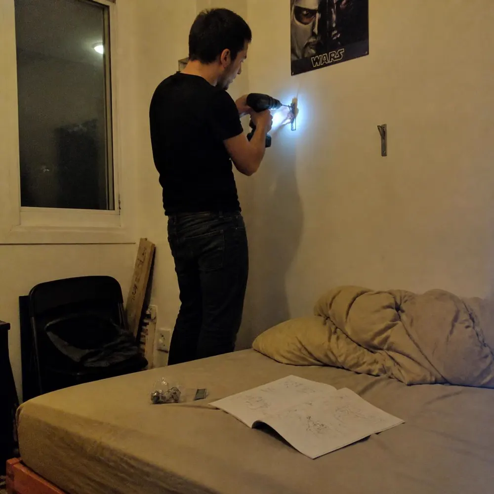 Hombre instalando una repisa angosta en un dormitorio pequeño